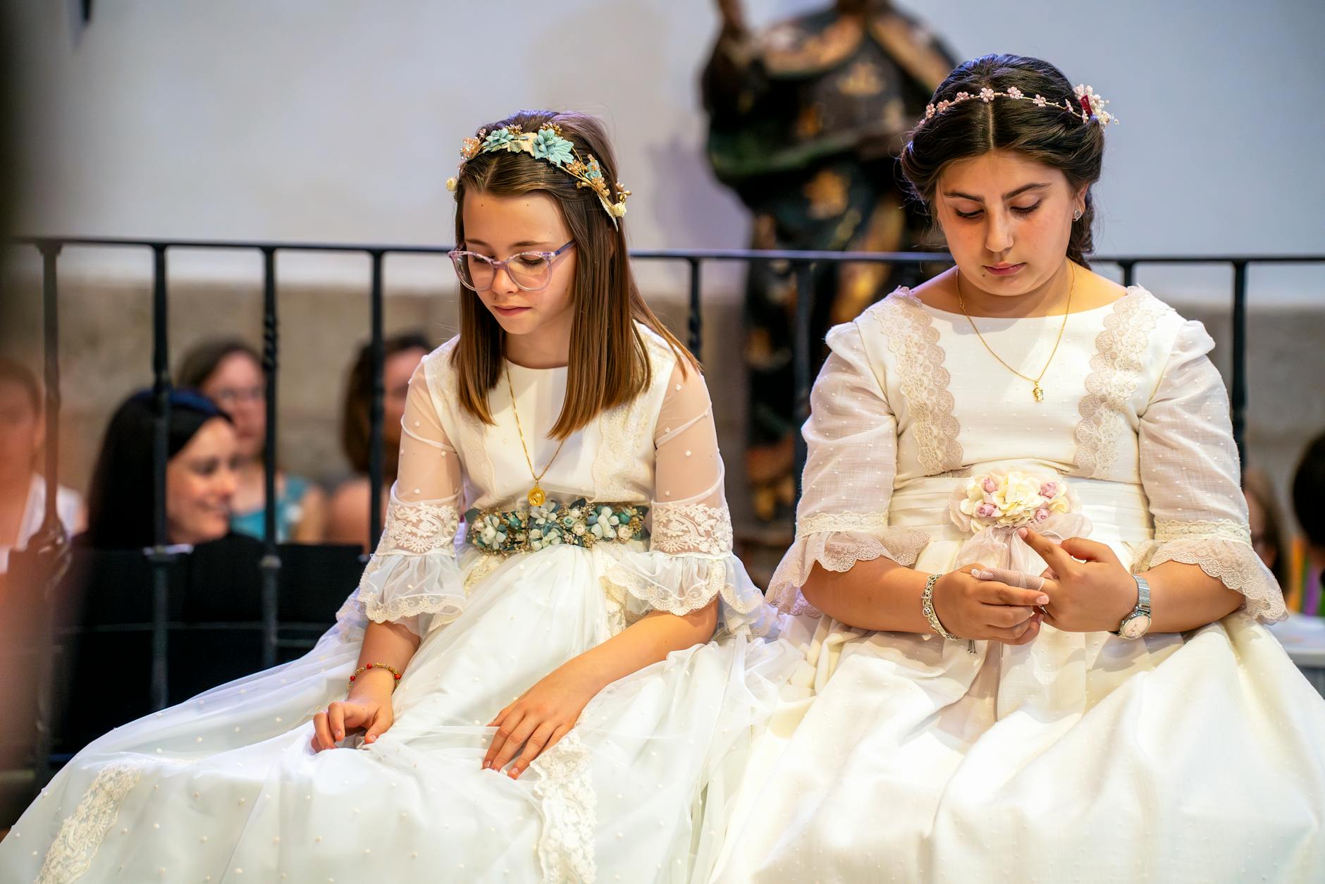 Dwie dziewczynki w białych sukienkach i wiankach podczas uroczystości