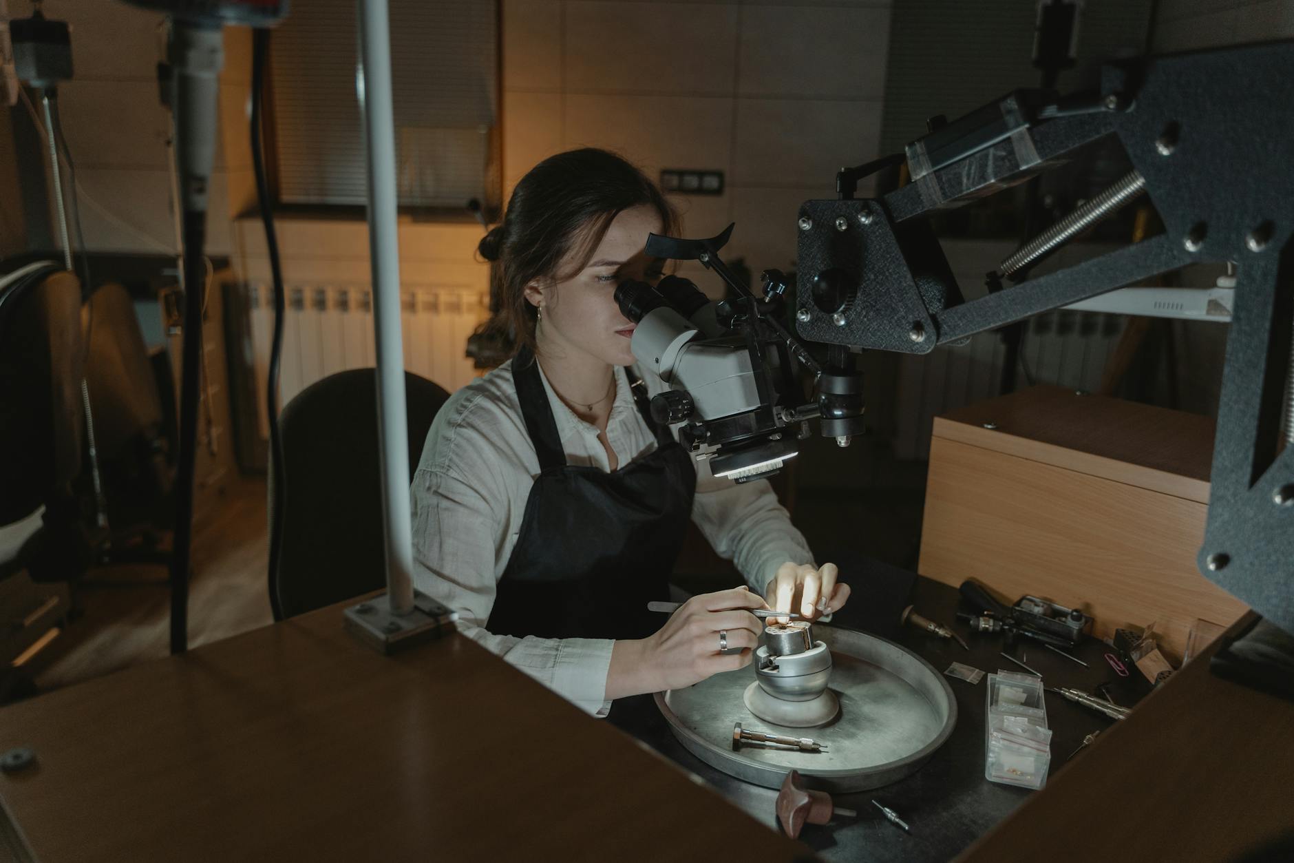 Jubilerka precyzyjnie obrabia złotą biżuterię pod mikroskopem