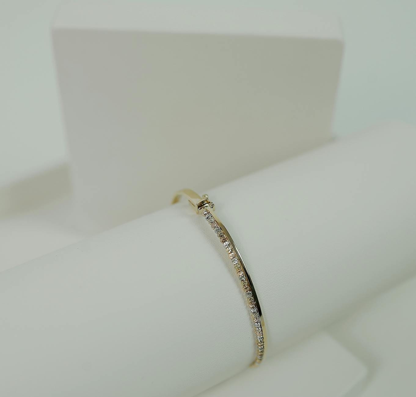 Zbliżenie złotej bransoletki wysadzanej diamentami na białym tle