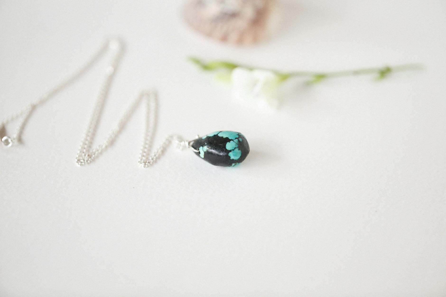 Detaliczny zbliżenie turkusowego wisiorka na delikatnym łańcuszku