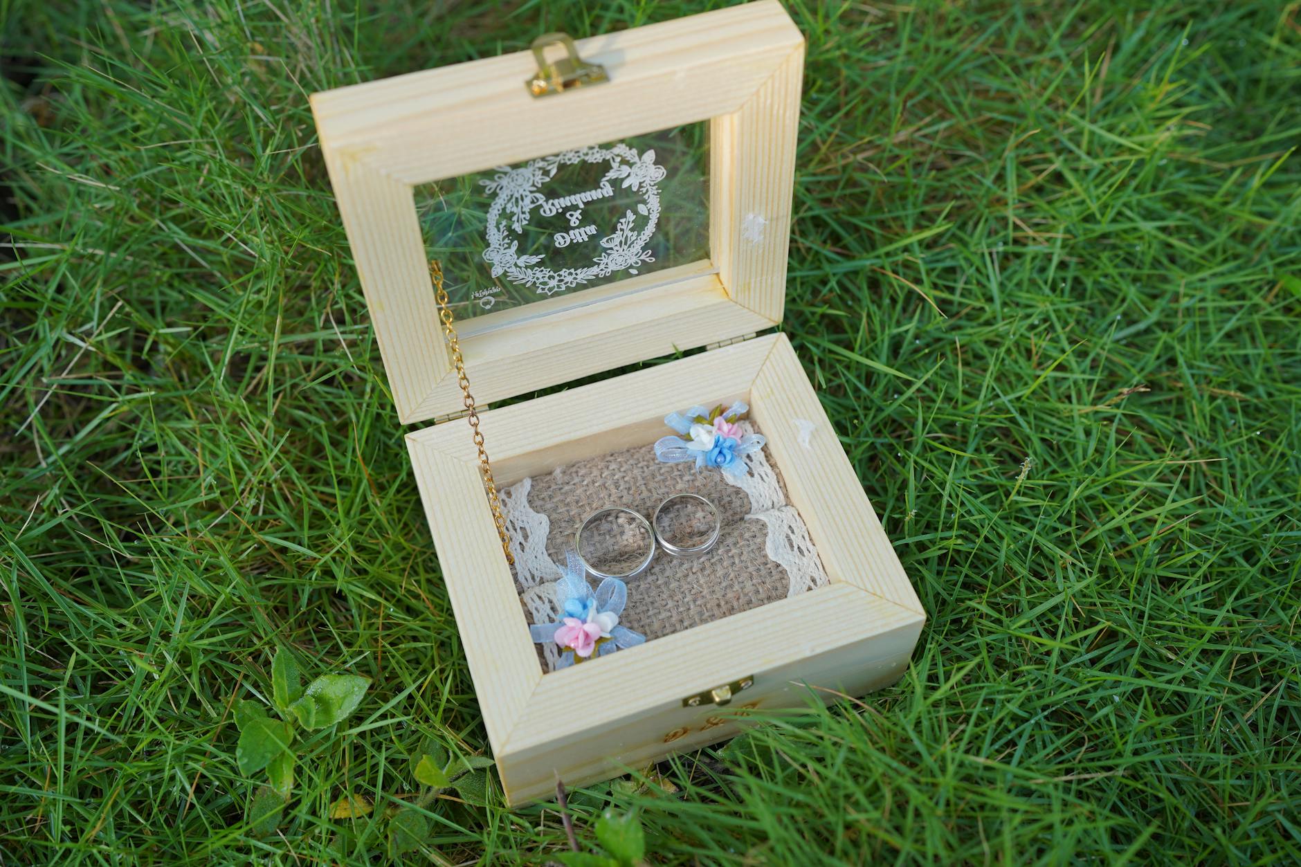 Drewniane pudełko ślubne z obrączkami na trawie