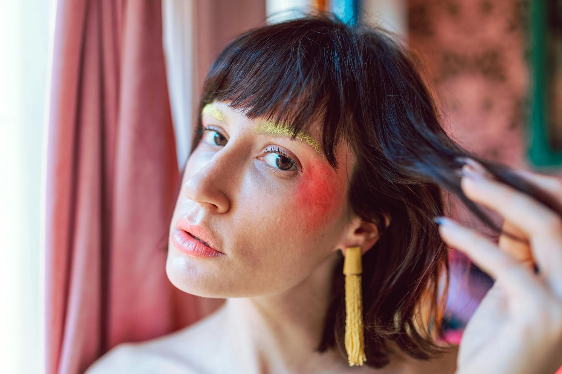 Kobieta w kolorowym makijażu prezentuje kolczyki z chwostami