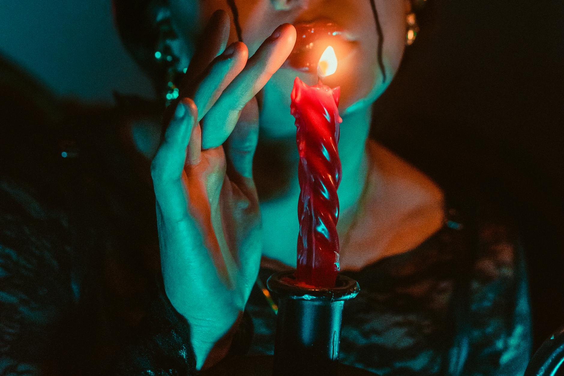 Osoba przy zapalonej świecy w mrocznym, gotyckim klimacie