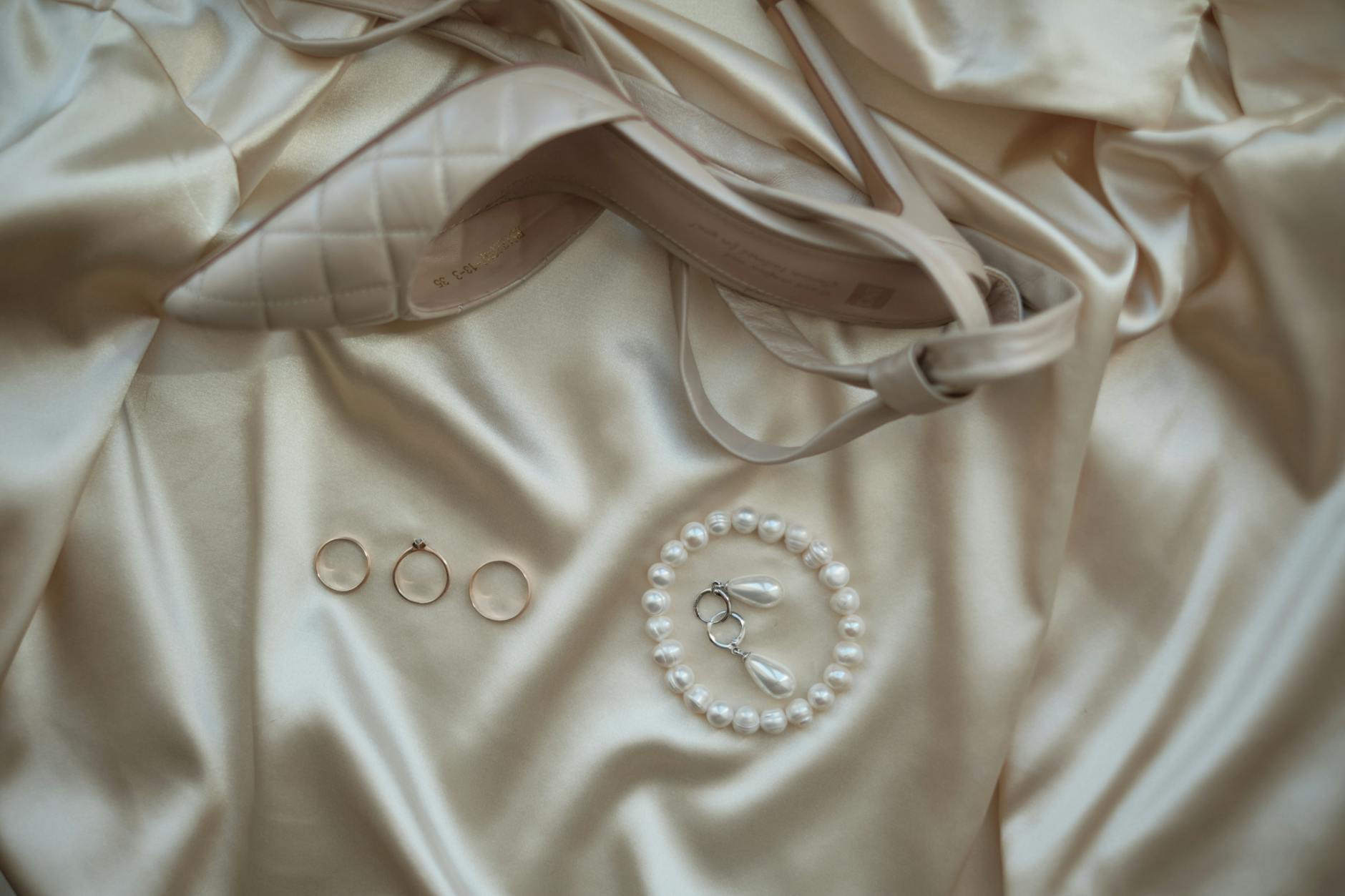 Perłowe kolczyki ślubne przy szpilkach na satynowej tkaninie