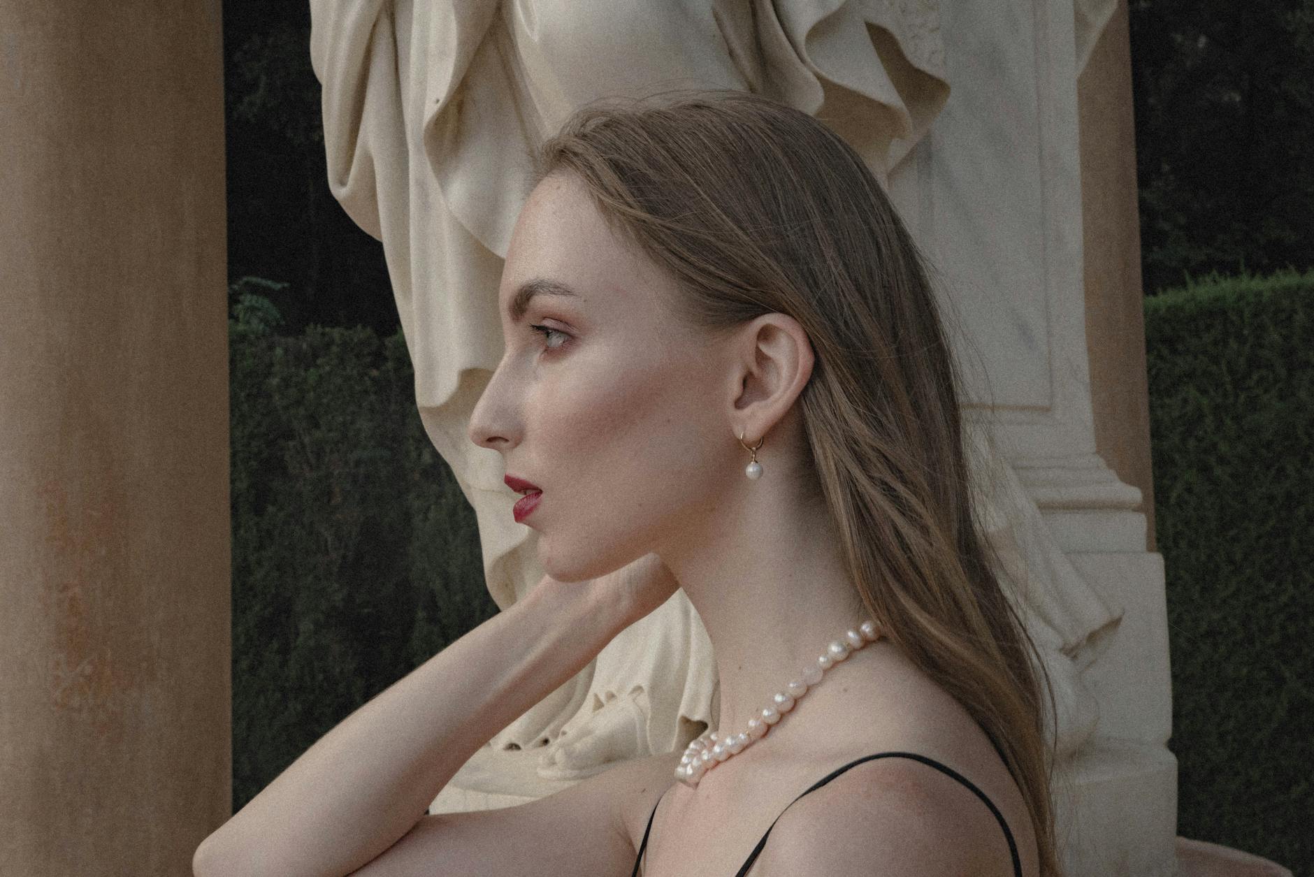 Profil kobiety w perłowej biżuterii w klasycznym ogrodzie