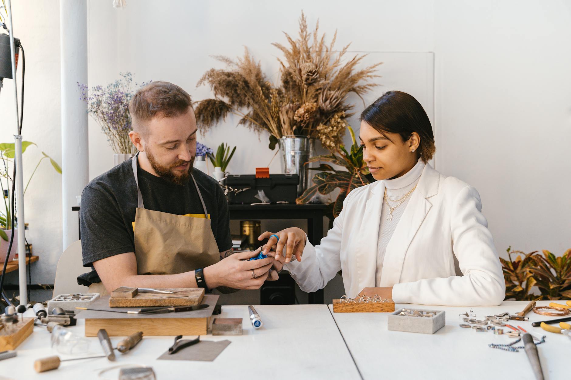 Rękodzielnik pokazuje klientce ręcznie robione kolczyki w pracowni