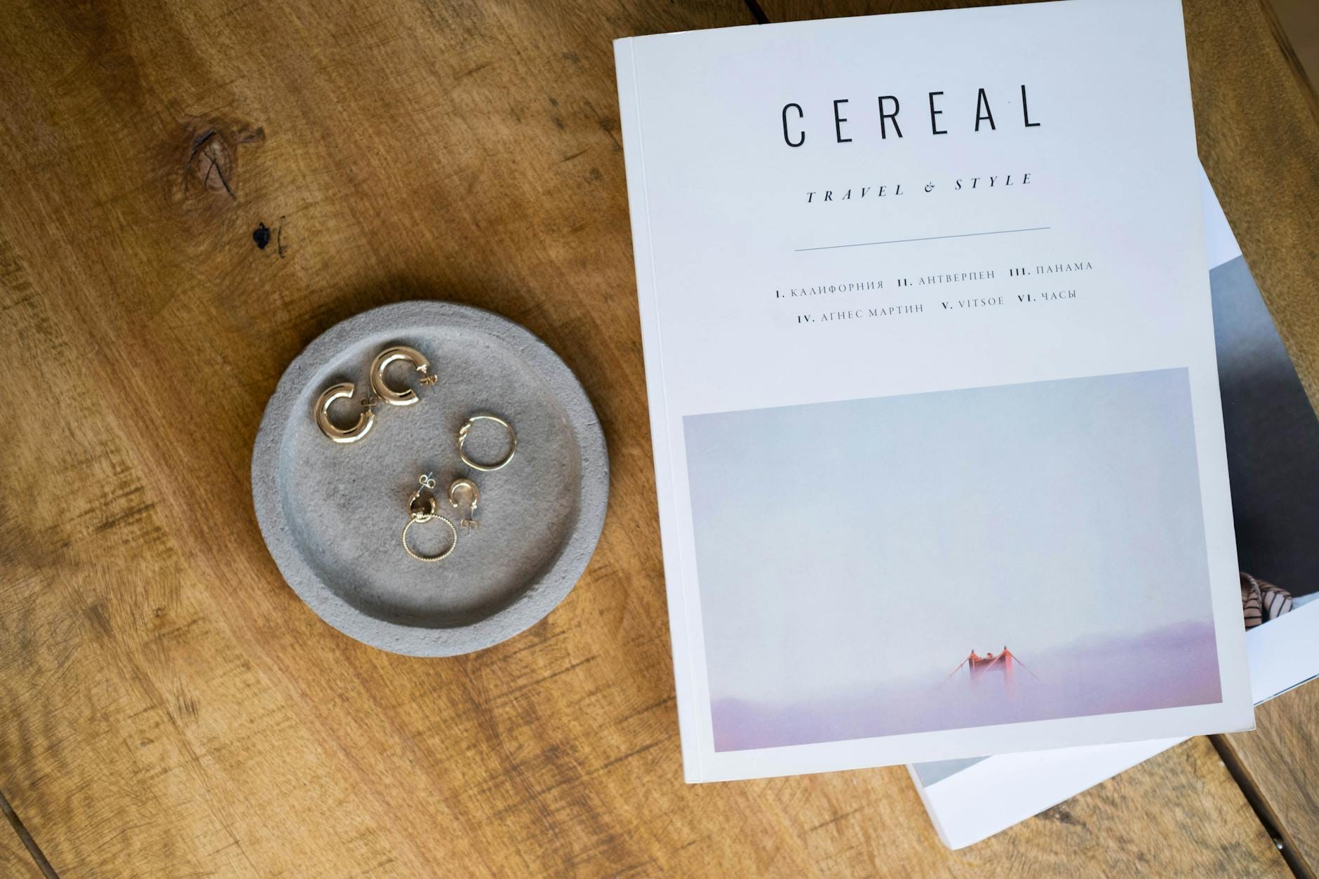 Złota biżuteria na drewnianym blacie obok magazynu lifestyle