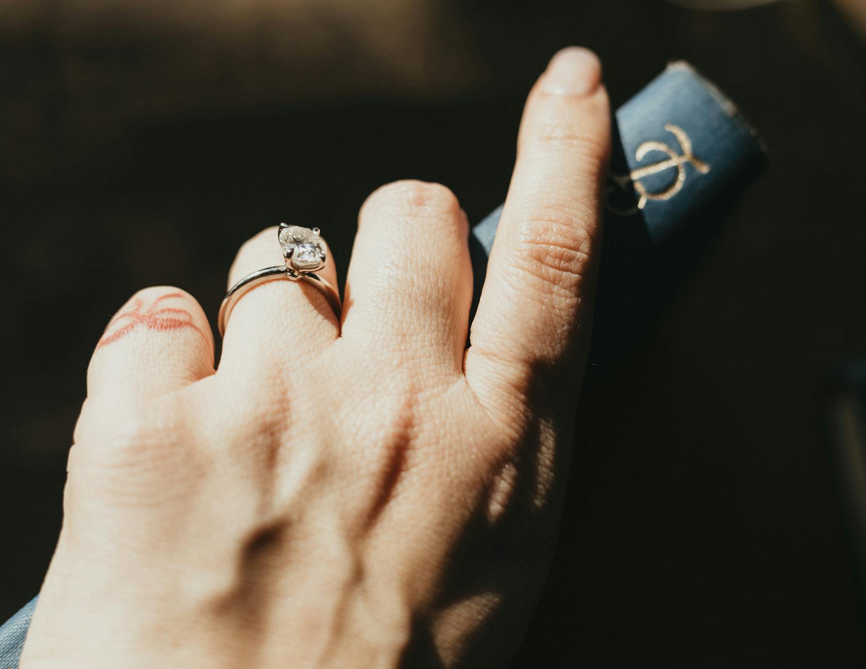 Dłoń z pierścionkiem zaręczynowym vintage trzyma stary ozdobny tom