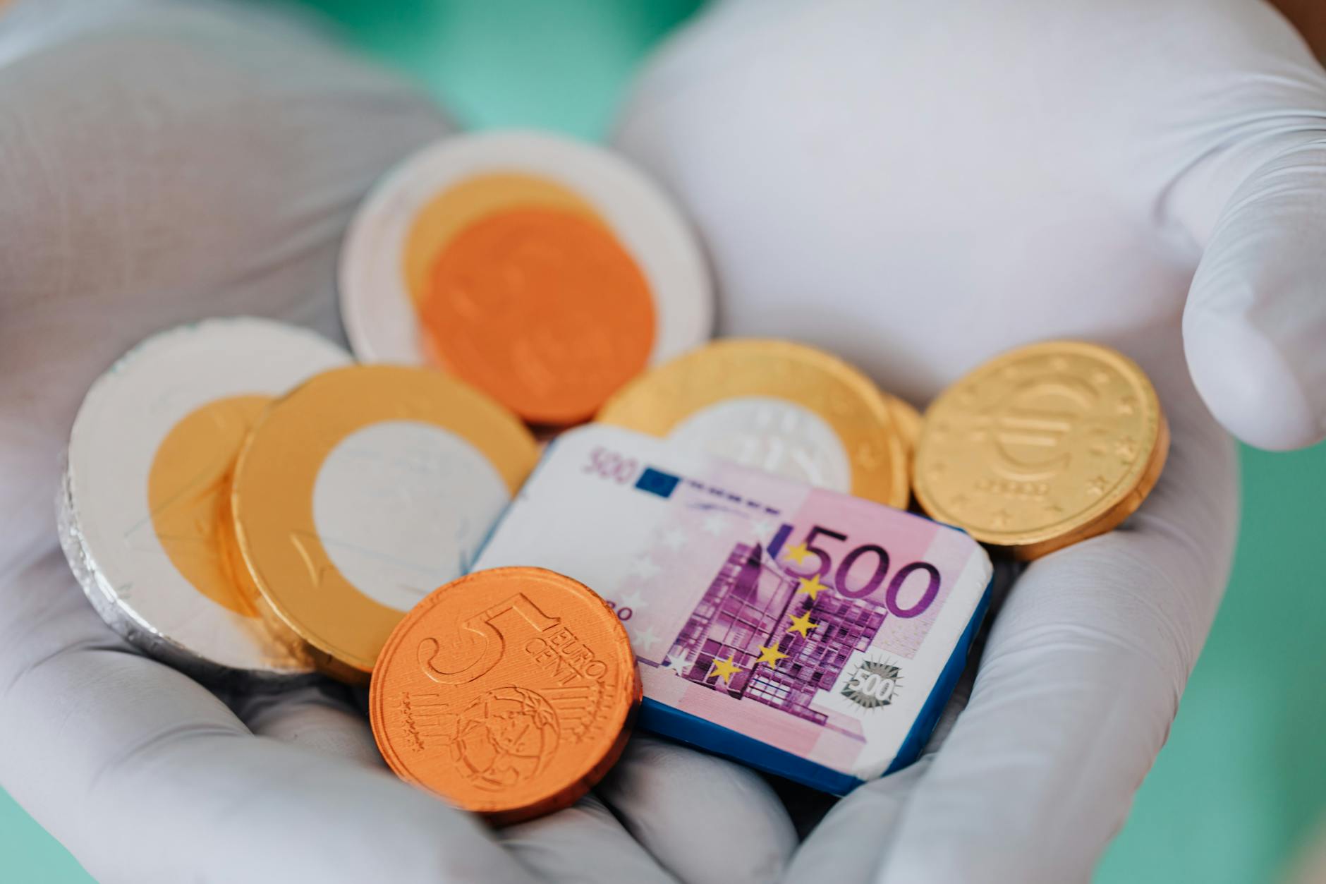 Ręka w rękawiczce trzymająca czekoladowe monety i banknot 10 euro