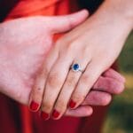 Najpopularniejsze kamienie w pierścionkach: znaczenie, symbolika i trwałość Dłoń kobiety z pierścionkiem z szafirem symbolizującym miłość i zaręczyny