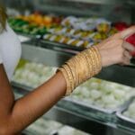Jak uniknąć błędów przy pierwszym zakupie złotej biżuterii: poradnik dla początkujących Kobieta w złotych bransoletkach ogląda słodycze na kolorowym bazarze