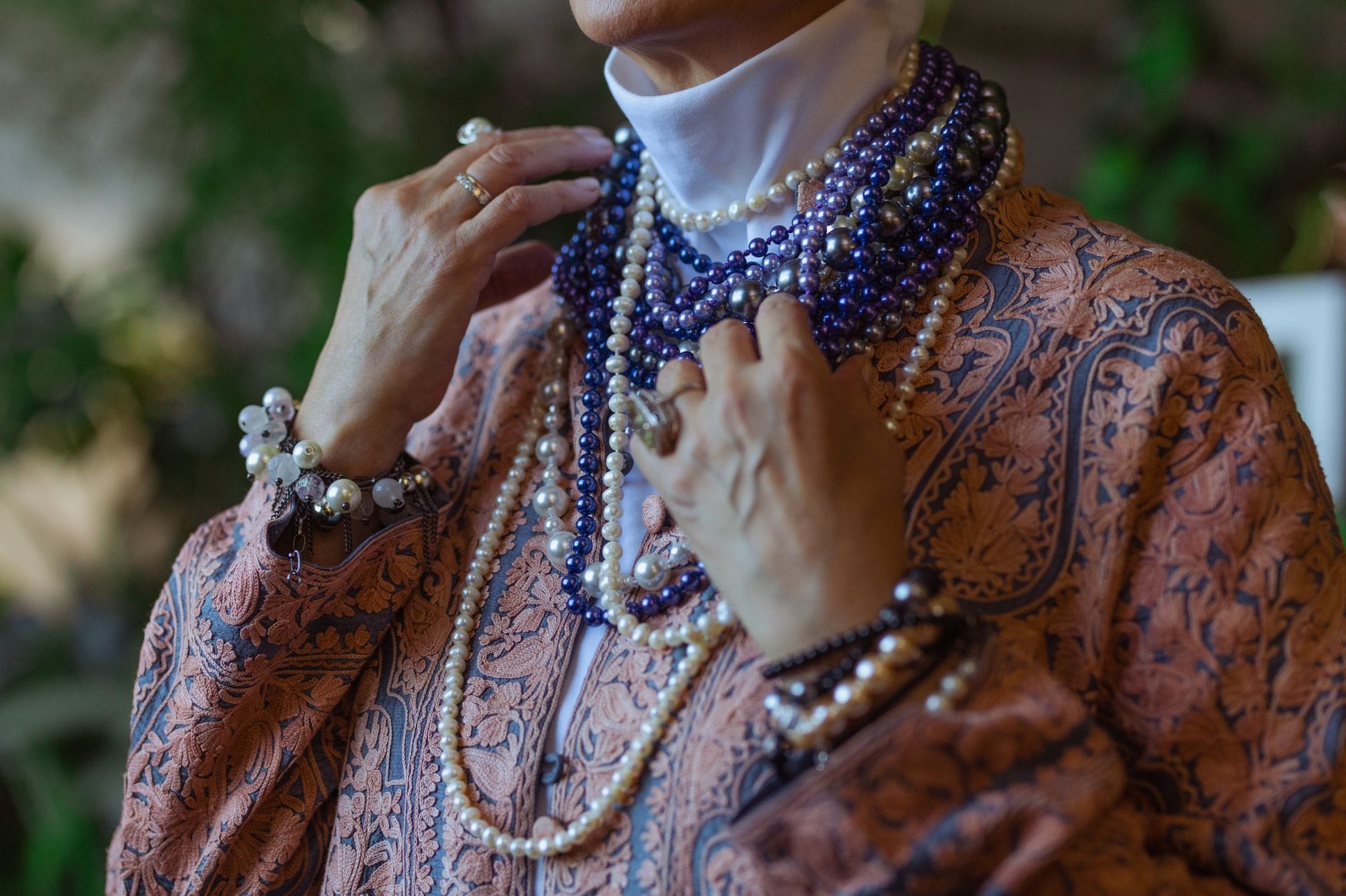 Starsza kobieta w wielu sznurach pereł i koralików w stylu boho